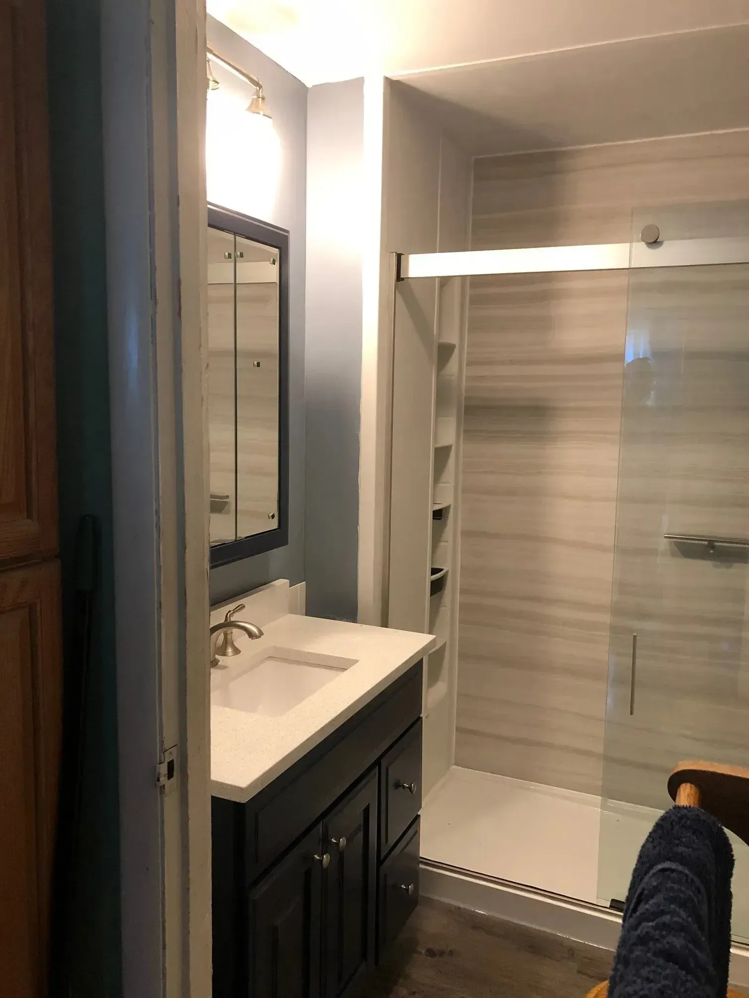 A bathroom with a sink , mirror and shower.
