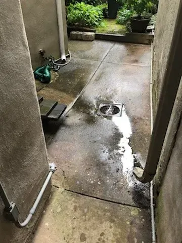 A concrete walkway with a drain in the middle of it.