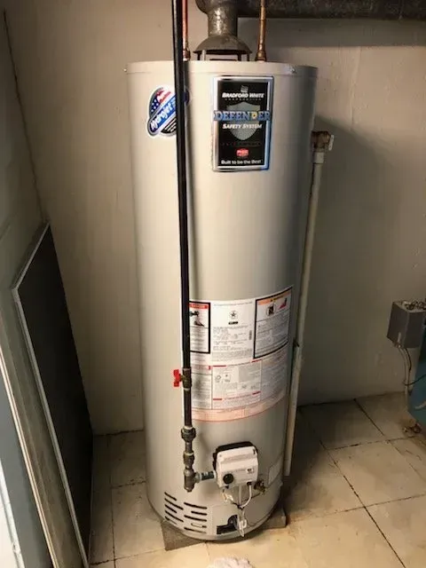 A water heater is sitting on a tiled floor in a room.