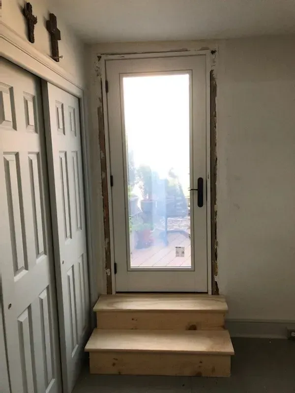 A white door with a glass window and wooden steps