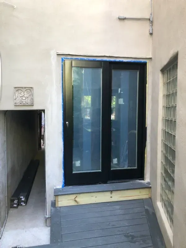 A black door is being installed on the side of a building.
