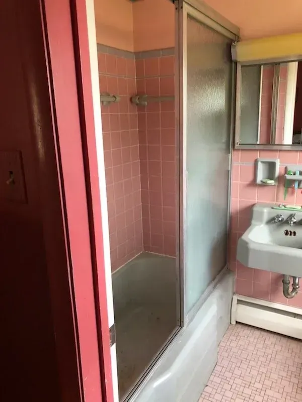 A bathroom with pink tiles and a sink and shower