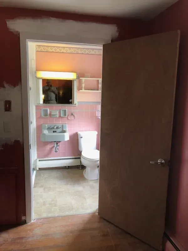 A bathroom with pink walls and a toilet and sink