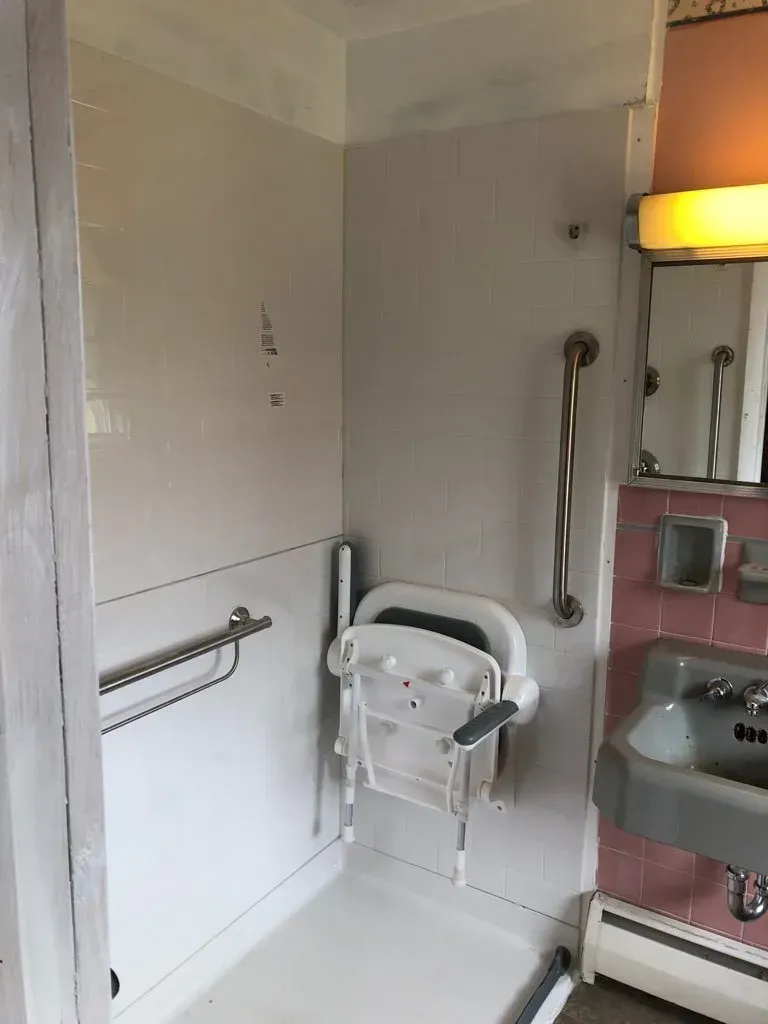 A bathroom with a shower , sink and mirror.