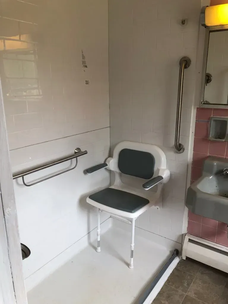 A bathroom with a shower chair and a sink.