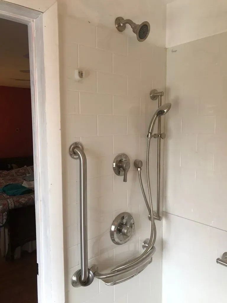 A shower with a hand rail and a shower head.