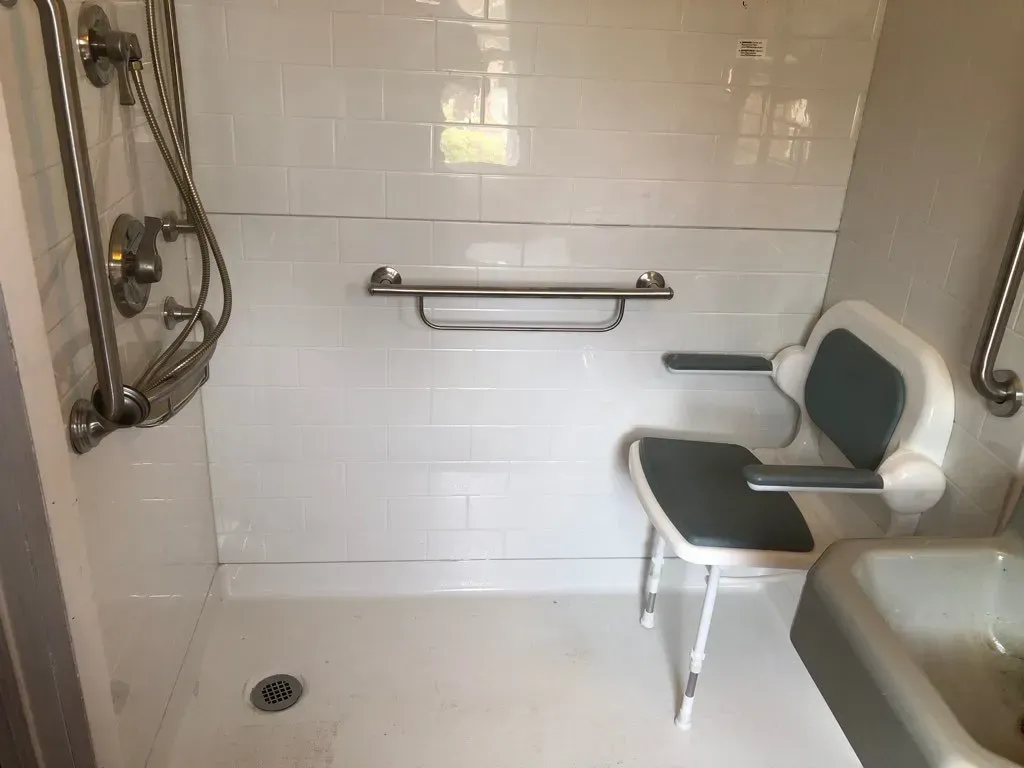A bathroom with a shower , tub , and chair.