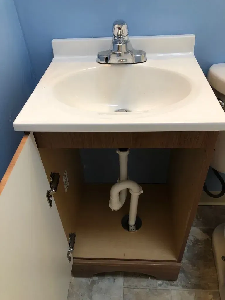 A bathroom sink with a plumbing pipe underneath it