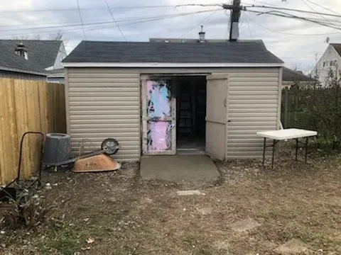 A small shed in a backyard with a table in front of it.