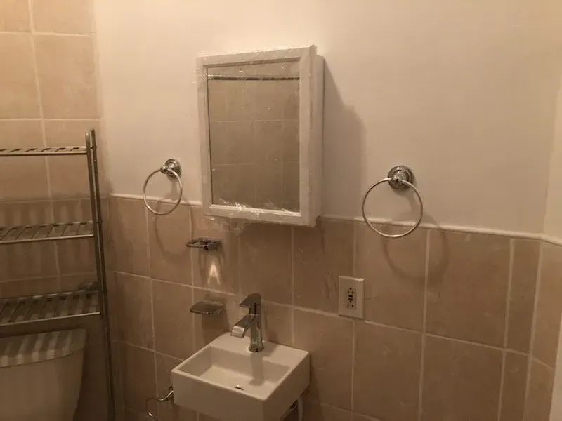 A bathroom with a sink , mirror and towel rack.