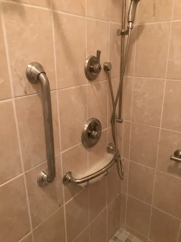 A shower with a hand rail and a shower head.