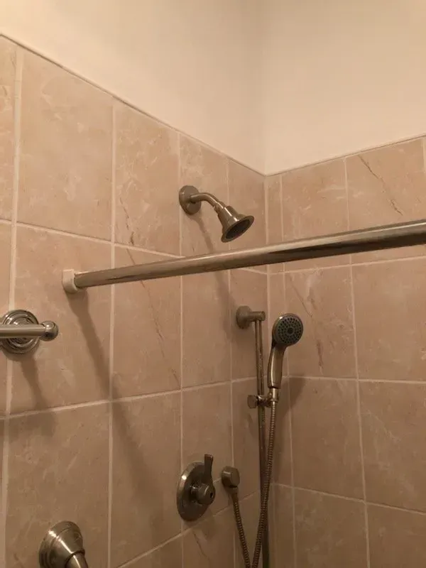 A bathroom with two shower heads and a shower curtain.