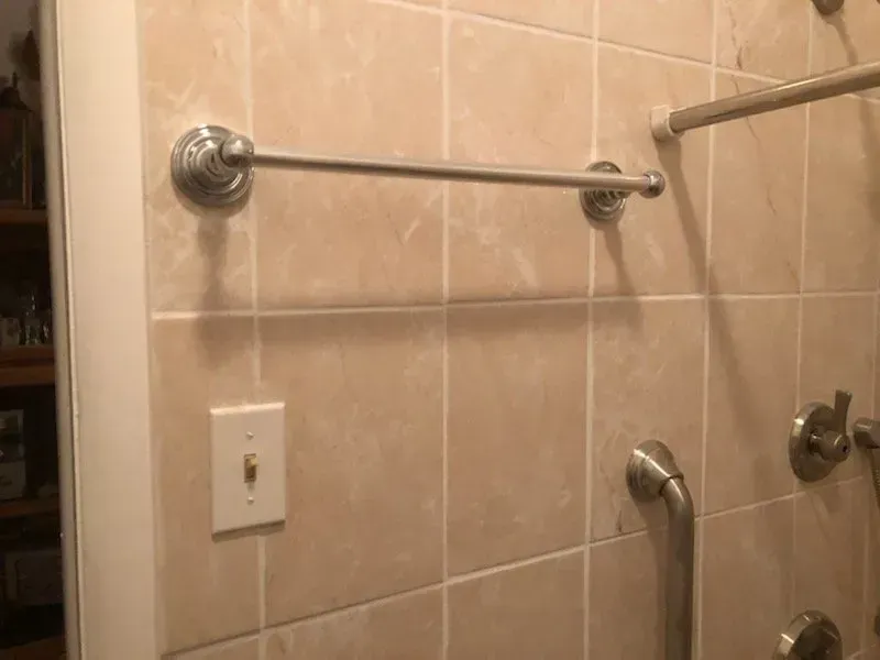A bathroom with a towel rack and a shower head.