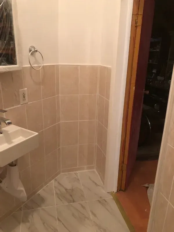 A bathroom with a sink , mirror and door.