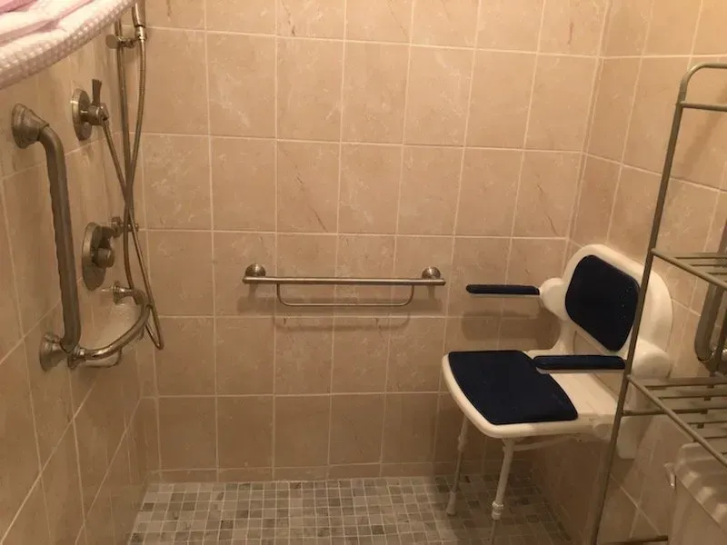 A handicapped bathroom with a shower and a chair.