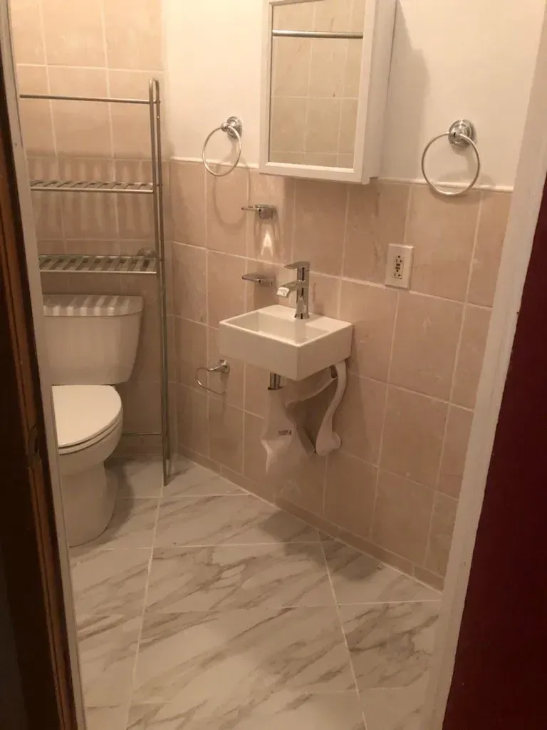 A bathroom with a toilet , sink and mirror.