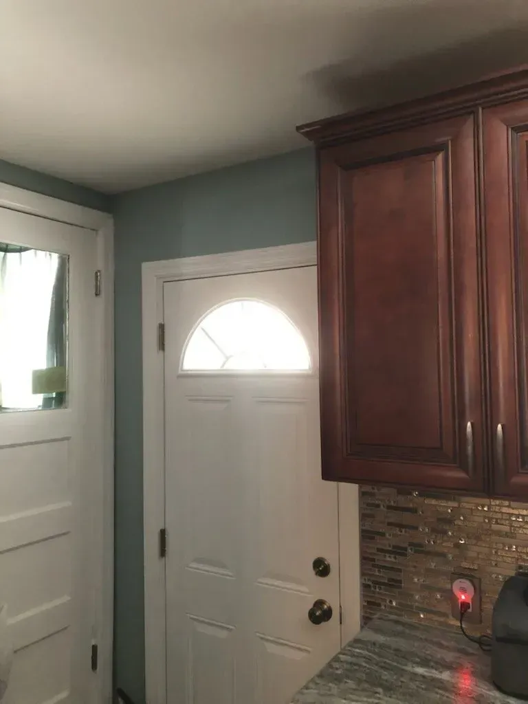 A kitchen with wooden cabinets and a door with a window.