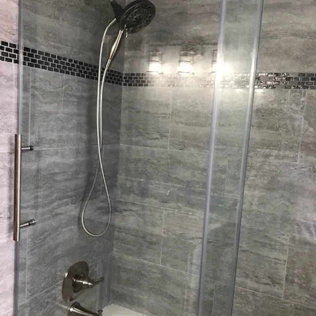 A shower with a glass door and a shower head