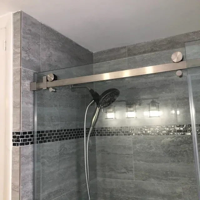 A shower with a sliding glass door and a shower head.