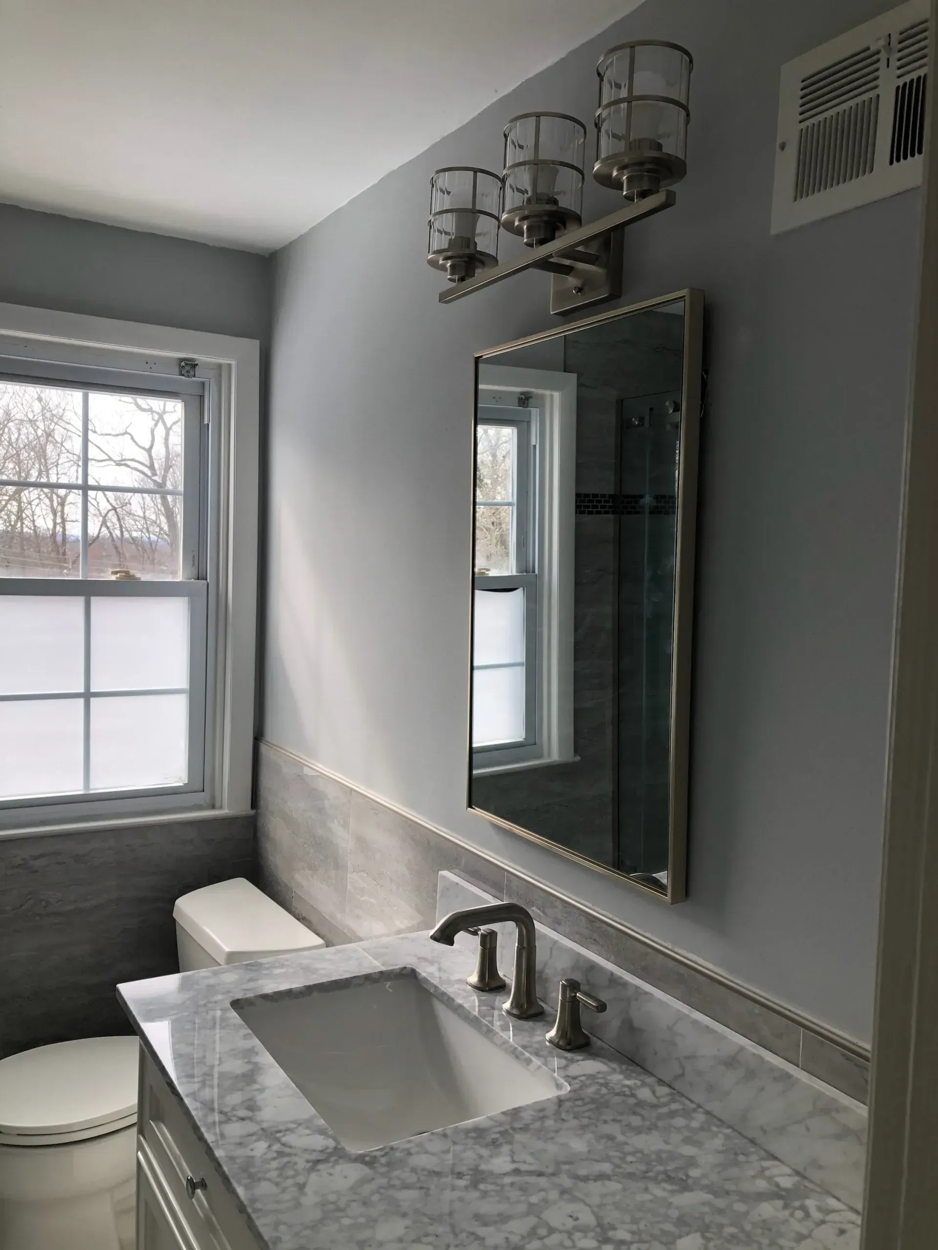 A bathroom with a sink a toilet and a mirror