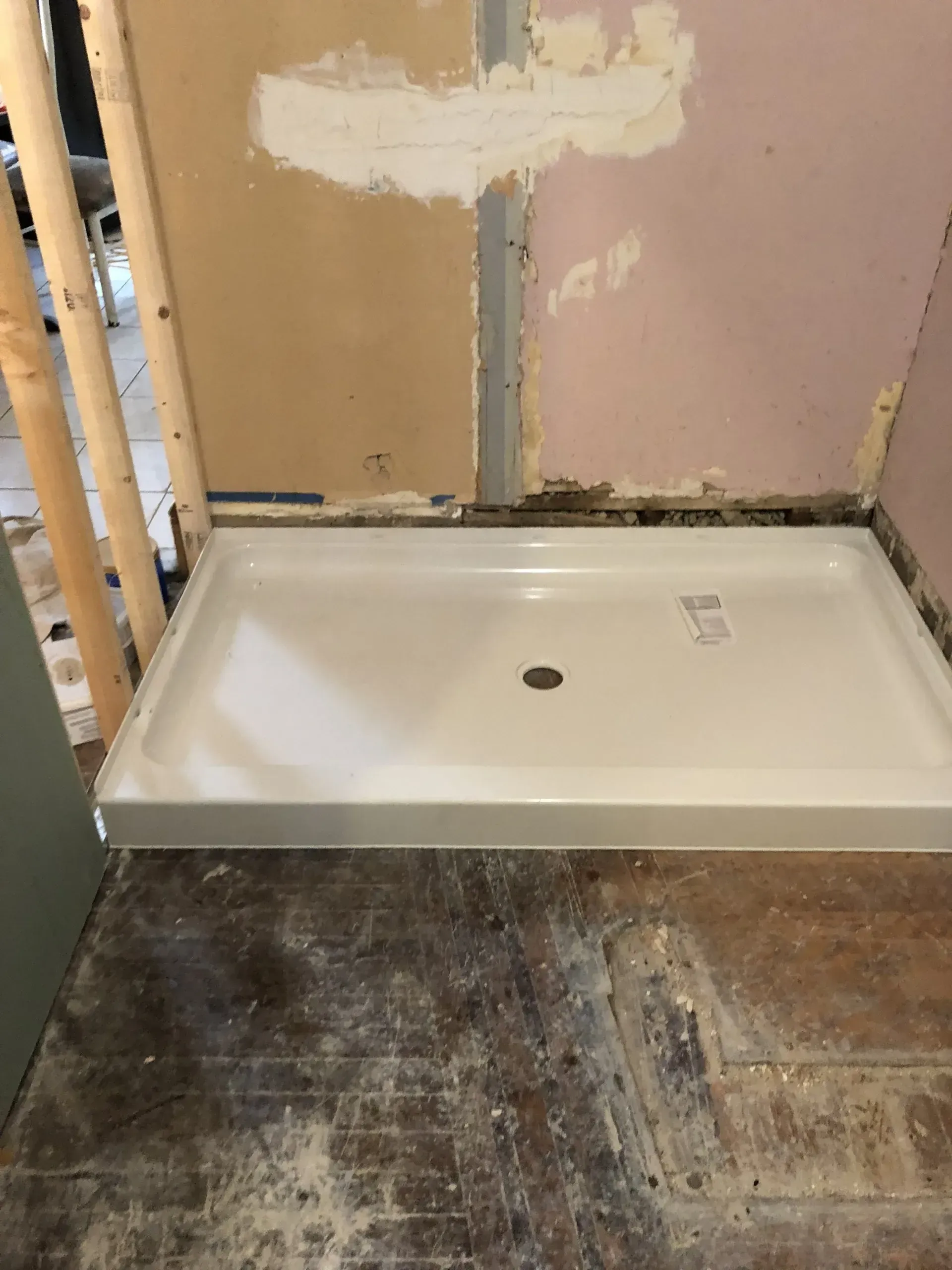 A shower tray is sitting on the floor in a bathroom under construction.