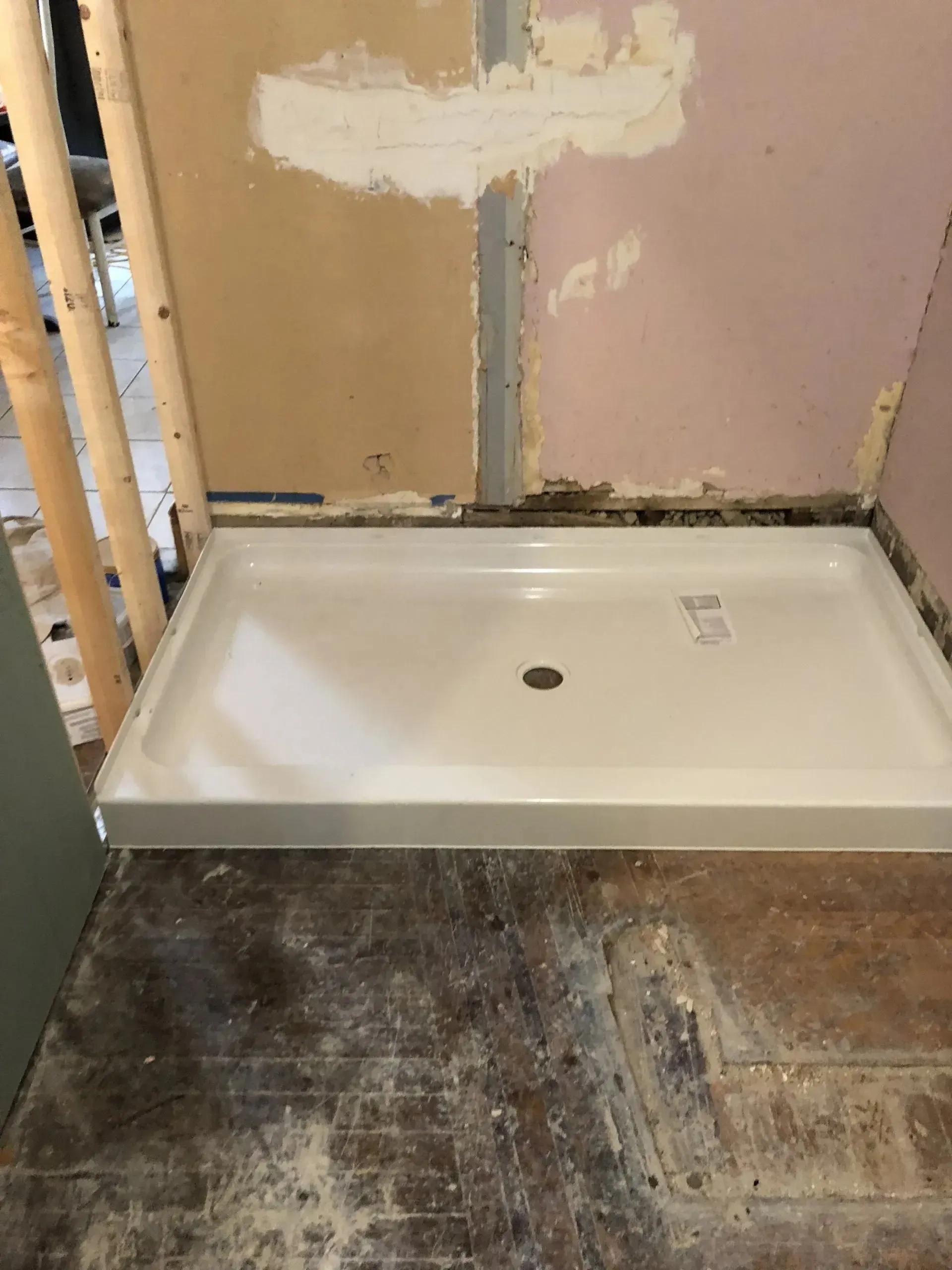 A shower tray is sitting on the floor in a bathroom under construction.