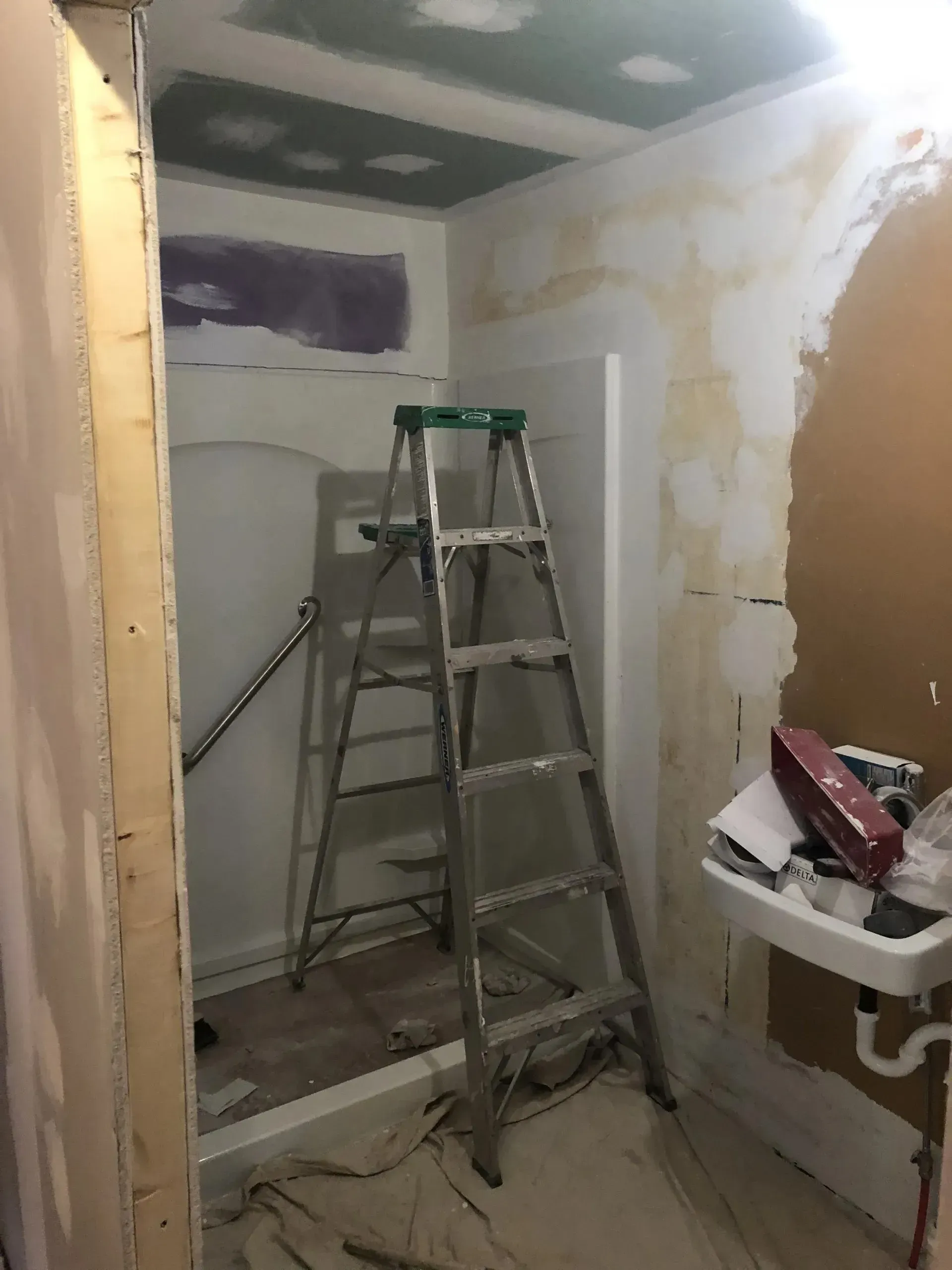 A bathroom under construction with a ladder and a sink.