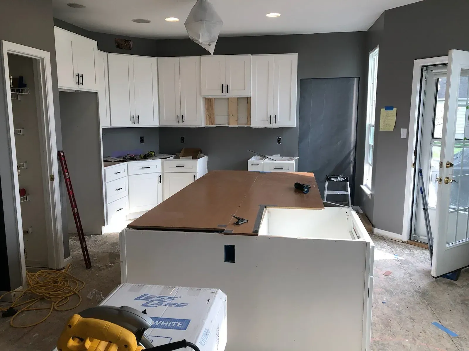 A kitchen under construction with white cabinets and a large island.