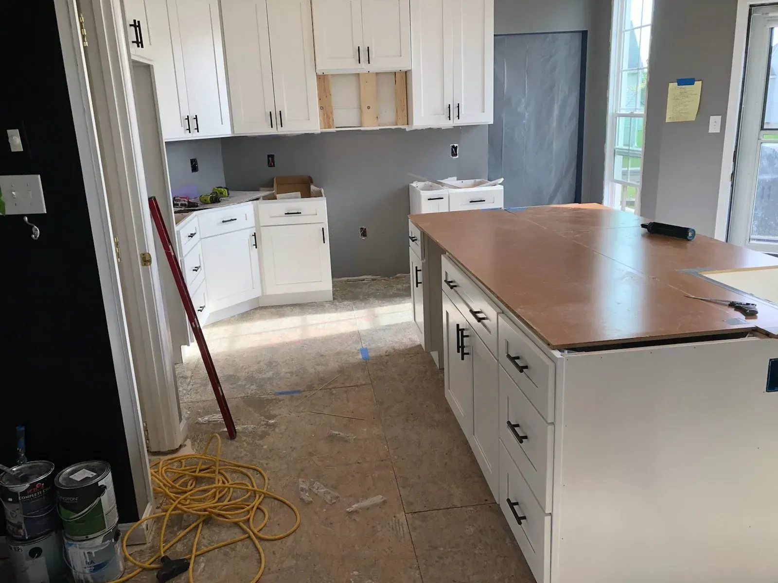A kitchen under construction with white cabinets and a large island.