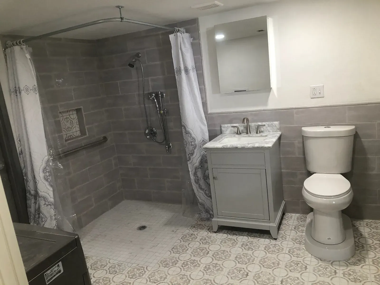 A bathroom with a toilet , sink , shower and mirror.