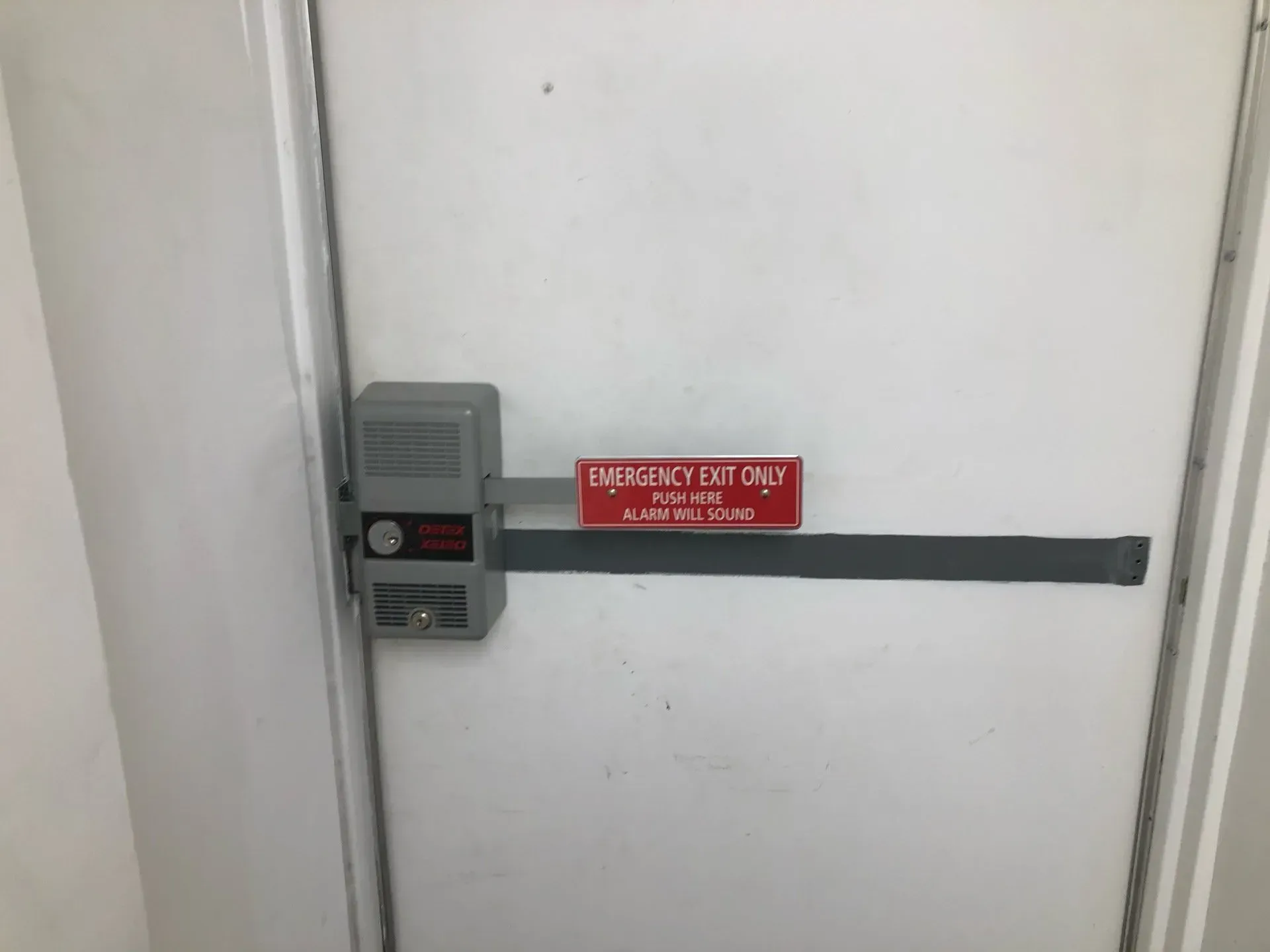 A white door with an emergency exit only sign on it