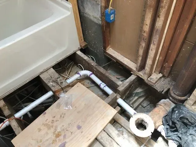A bathroom with a bathtub and pipes underneath it.