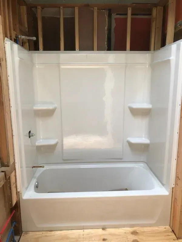A white bathtub is sitting in a bathroom under construction.