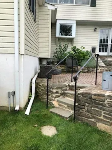 A house with a stone wall and stairs leading up to it.