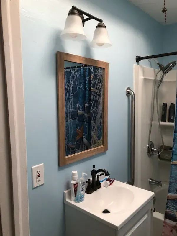 A bathroom with a sink , mirror and shower.