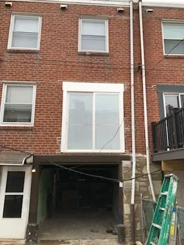A brick building with a garage underneath it and a ladder in front of it.