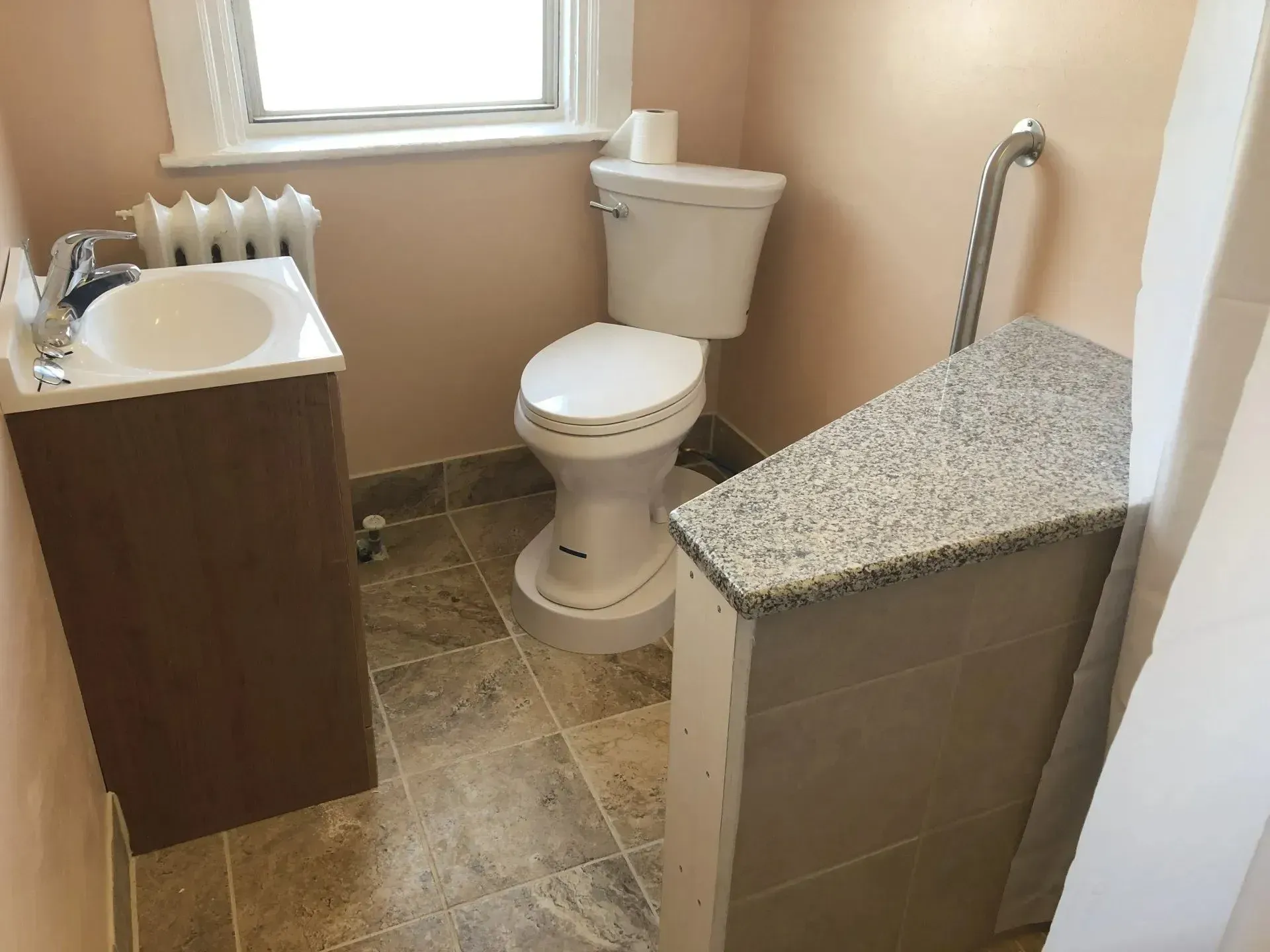 A bathroom with a toilet , sink , and window.