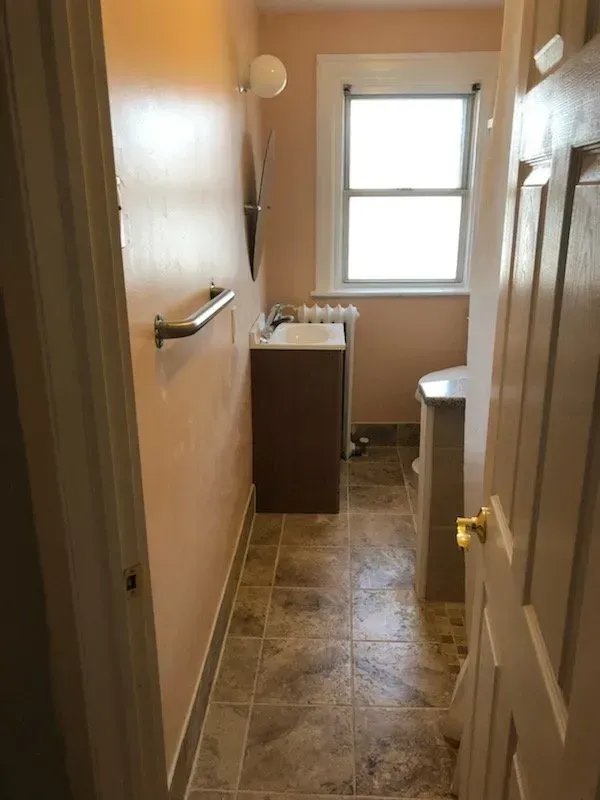 A bathroom with a sink , toilet , and window.