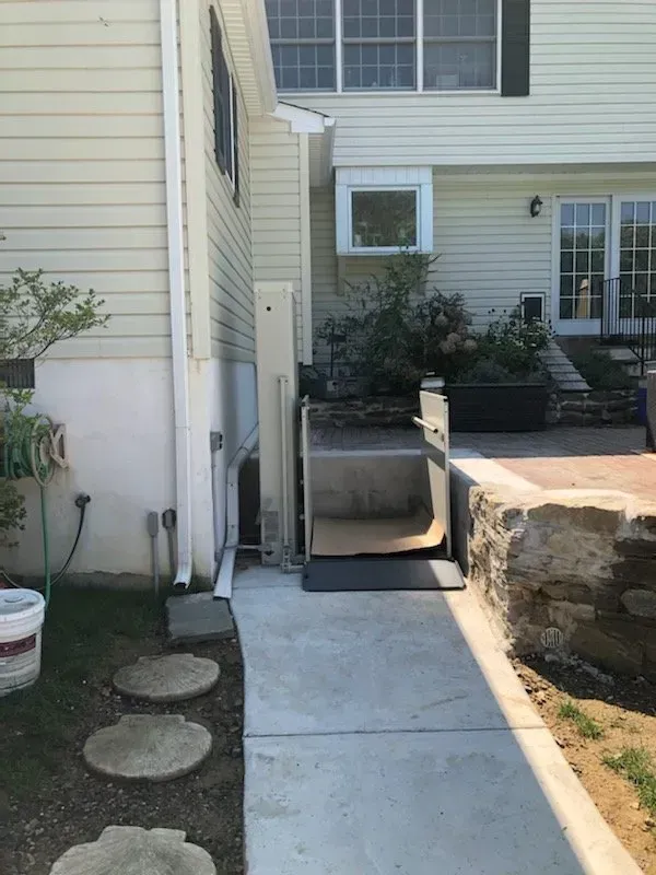 A concrete walkway leading to a house with a wheelchair lift.