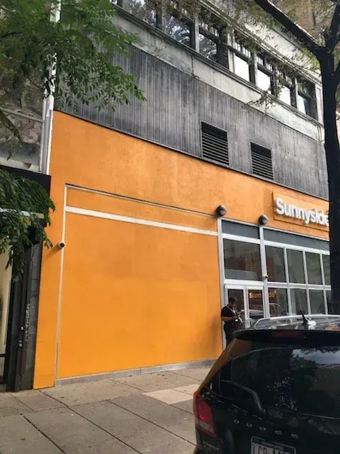 A car is parked in front of a building that says sunnyside.
