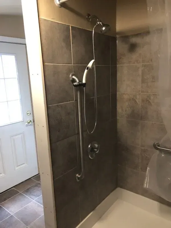 A bathroom with a walk in shower and a hand rail.
