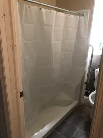 A bathroom with a shower stall and a toilet.