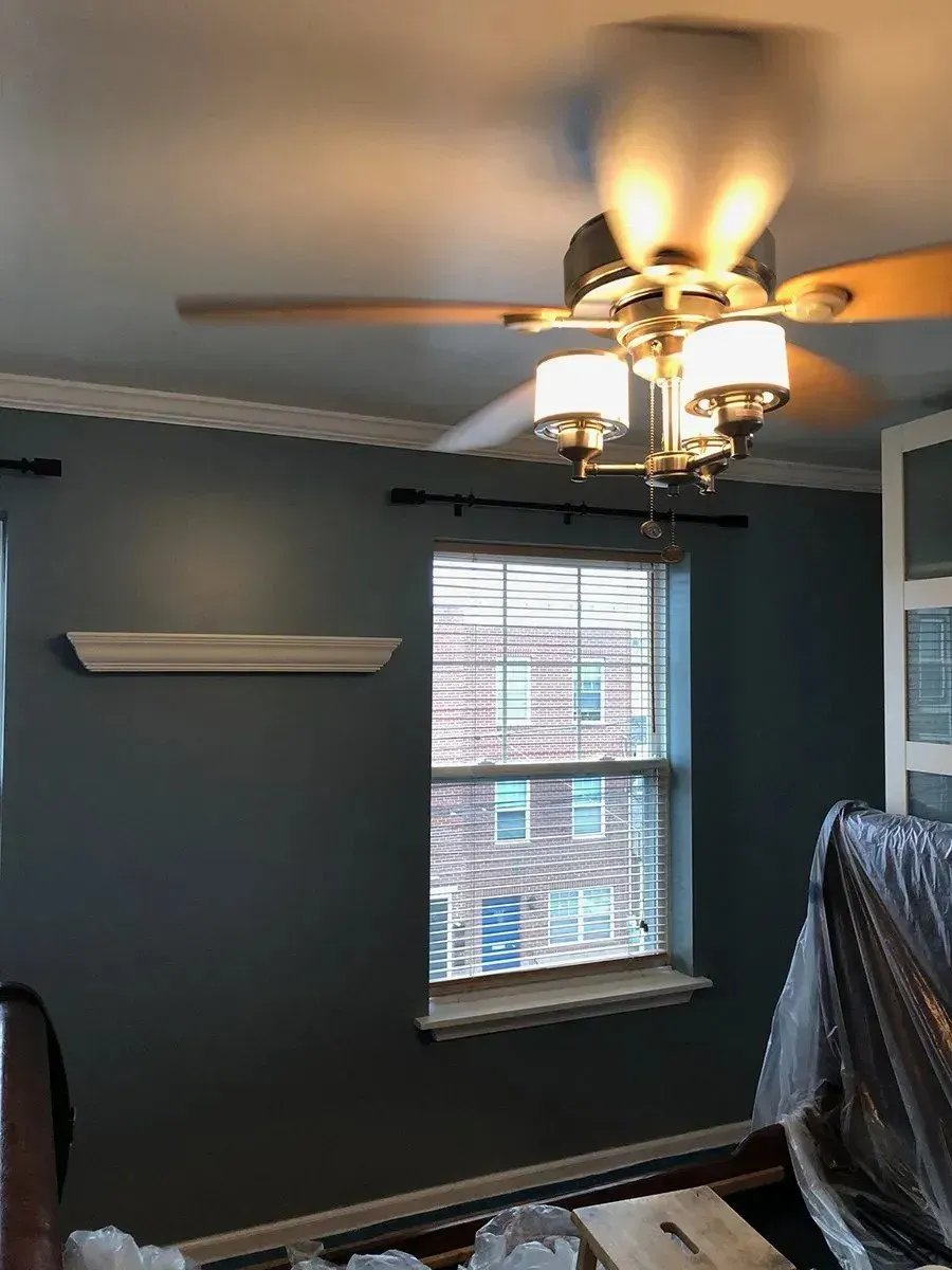 A room with a ceiling fan and a window.