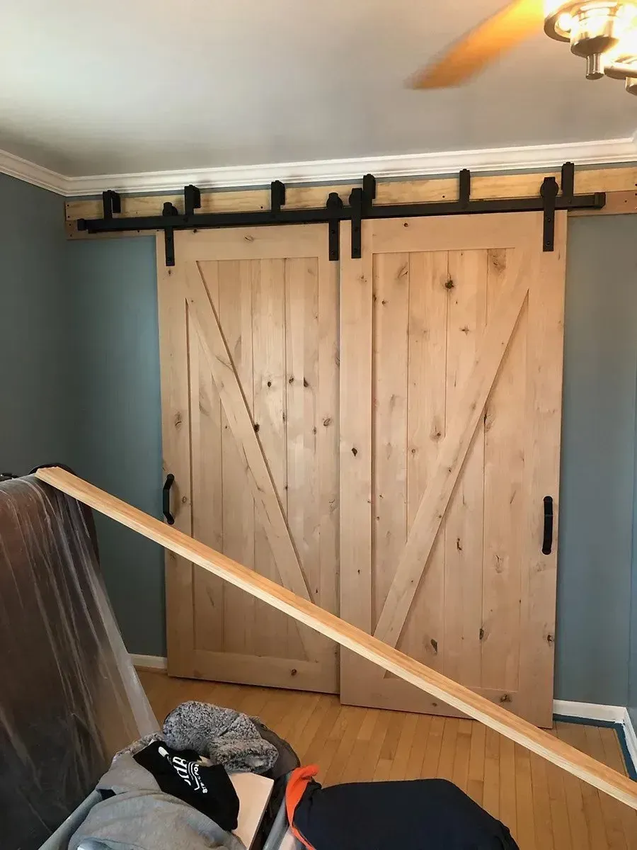 A bedroom with a sliding barn door and a ceiling fan.