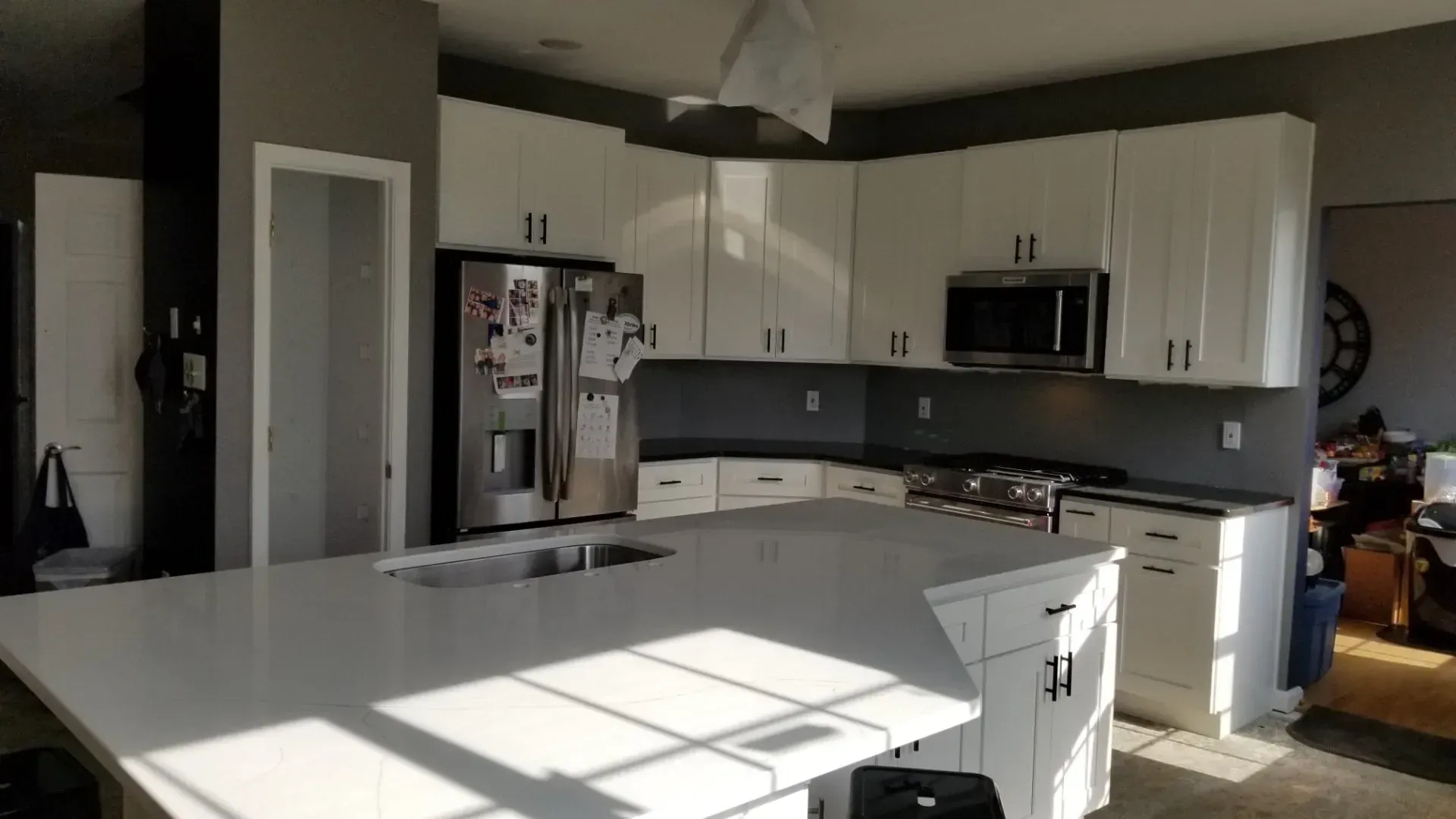 A kitchen with white cabinets , stainless steel appliances , and a large island.