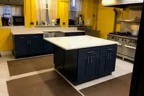 A kitchen with blue cabinets and a large island in the middle.