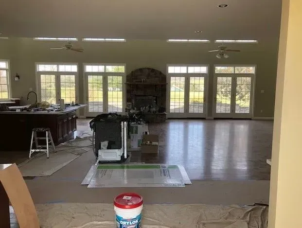 A large room with a lot of windows and a bucket of paint on the floor.