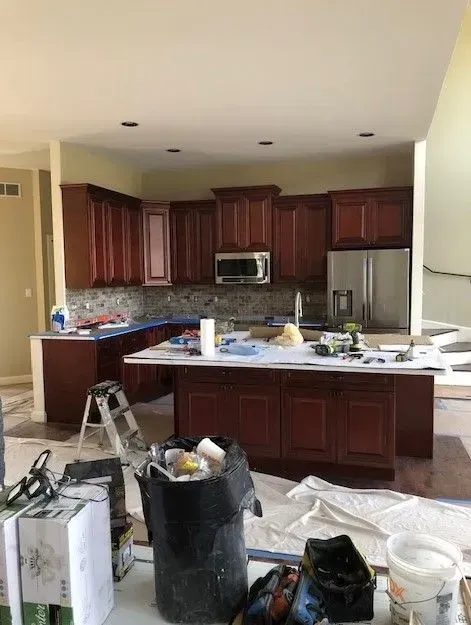 A kitchen is being remodeled with wooden cabinets and a large island.