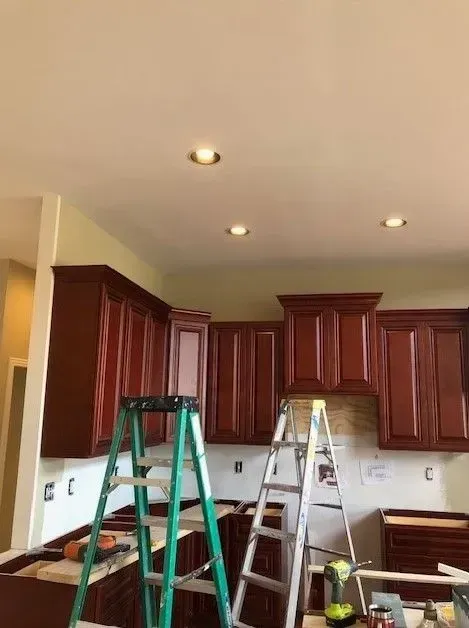 A kitchen is being remodeled and a ladder is sitting on the counter.