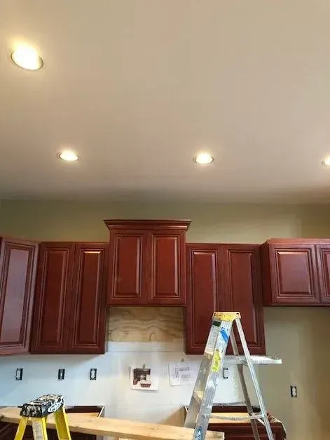 A kitchen with red cabinets and a yellow ladder.